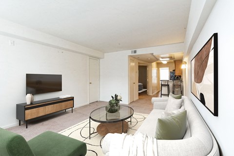 A living room with a white couch, a green chair, and a glass coffee table.