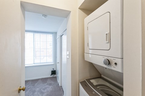 A small, clean, and modern kitchen with a washing machine and dryer built into the cabinetry.