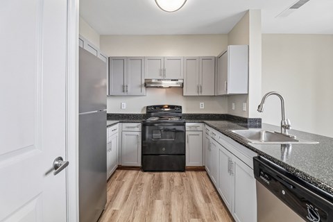 A kitchen with a black dishwasher and stove top oven.