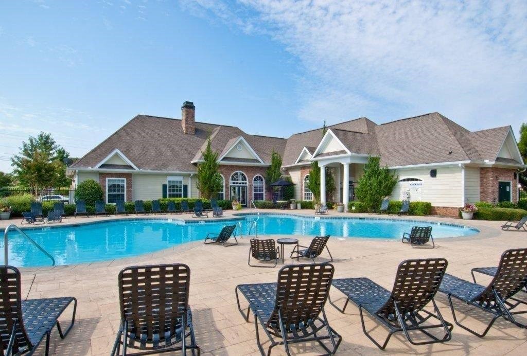 a swimming pool with chairs around it in front of a house at Alexander Ridge Apartments, Canton , Georgia