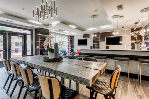 a dining area with a long table and chairs and a kitchen