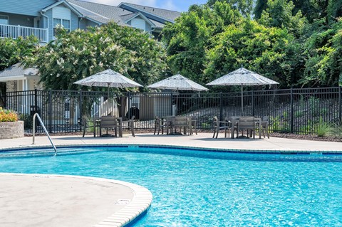 a swimming pool with patio furniture and umbrellas next to a resort style pool at St. Andrews Reserve, North Carolina, 28412