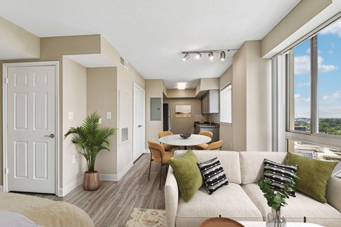 A well-lit living room with a couch, chairs, and a dining table.