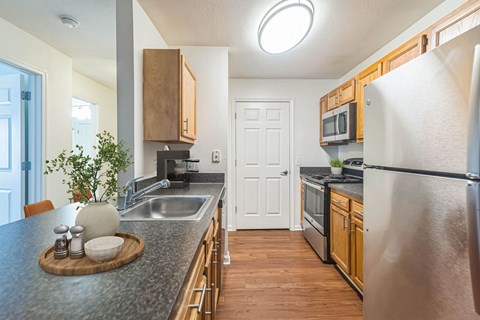 A kitchen with a stainless steel refrigerator and wooden cabinets.