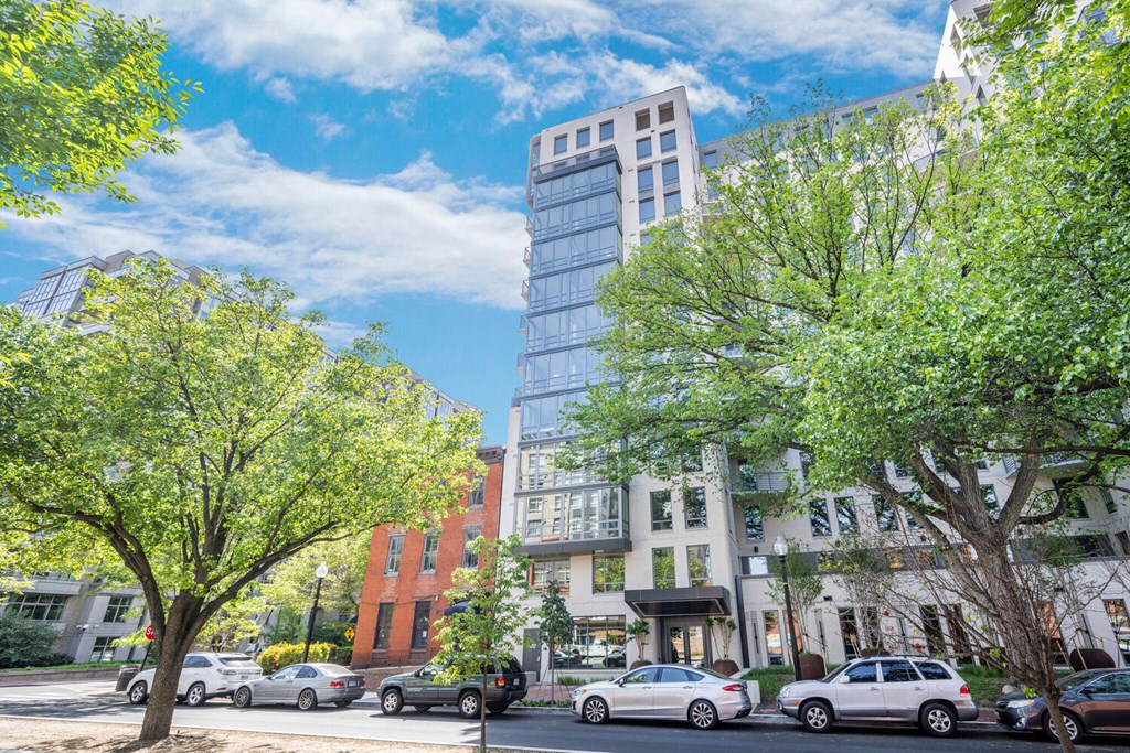 A street view with cars and trees in front of a building.