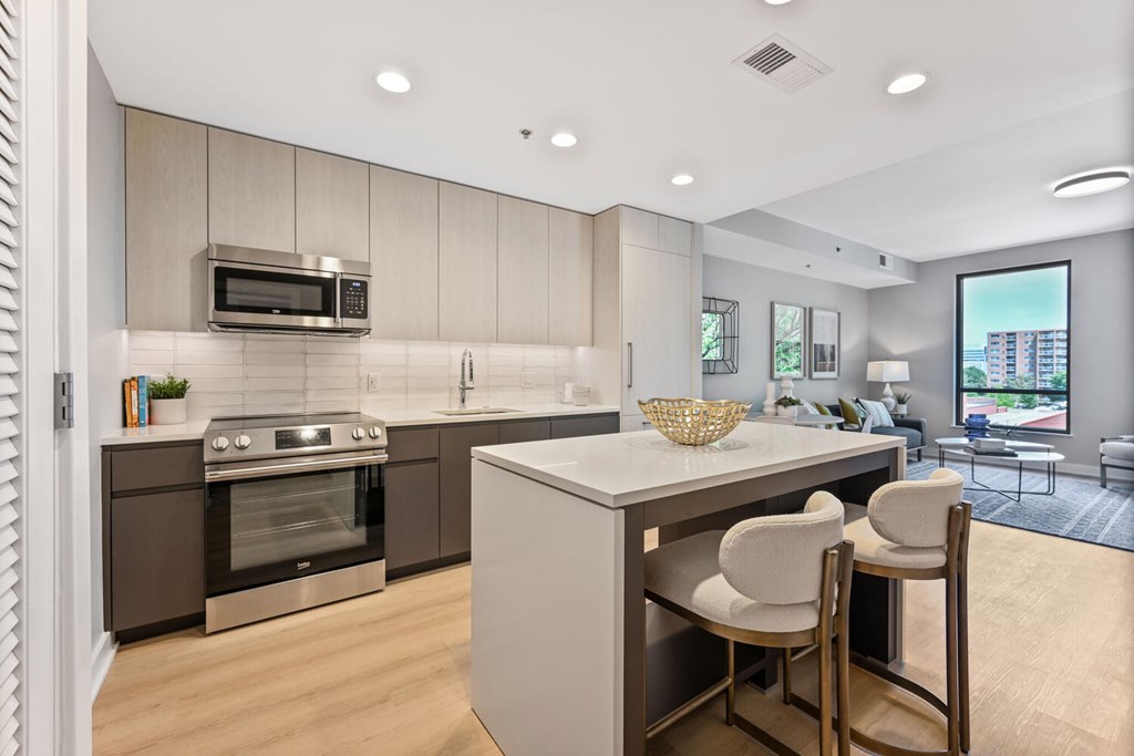 A modern kitchen with a large island and a stainless steel oven.