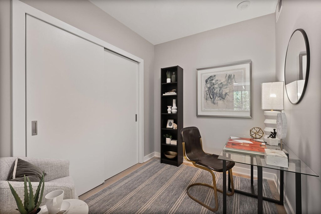 A modern living room with a chair, a table, a couch, a plant, and a framed picture on the wall.
