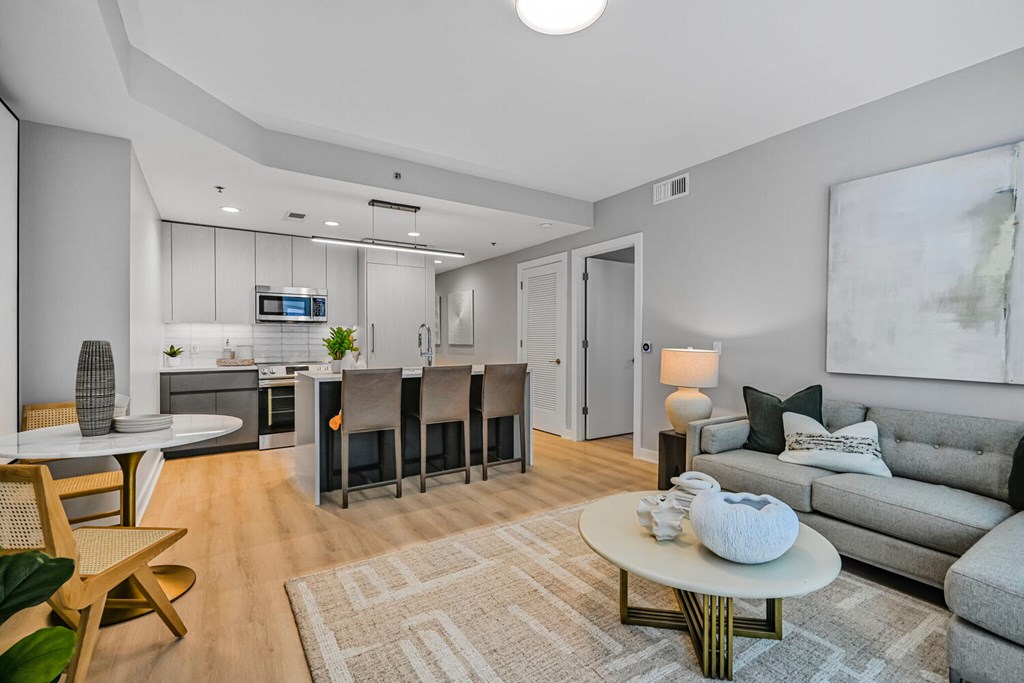 A modern living room with a grey couch, a white coffee table, and a wooden chair.