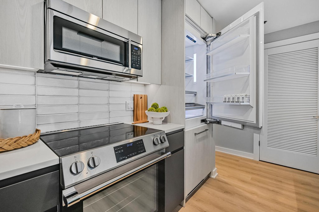 A modern kitchen with a stove, microwave, and refrigerator.