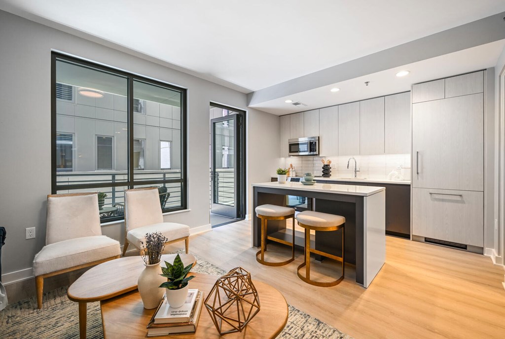 A modern kitchen with a bar stool and a table with a vase and a plant on it.