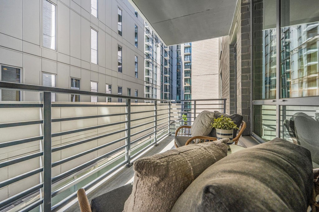 A balcony with a couch and pillows overlooking a cityscape.