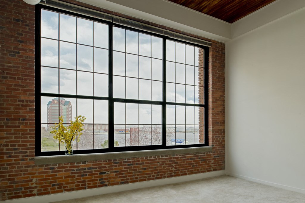 an empty room with a large window and a brick wall at Tindeco Wharf, Baltimore Maryland