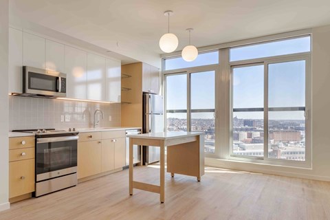 A kitchen with a microwave above the stove and a table in front of a window.