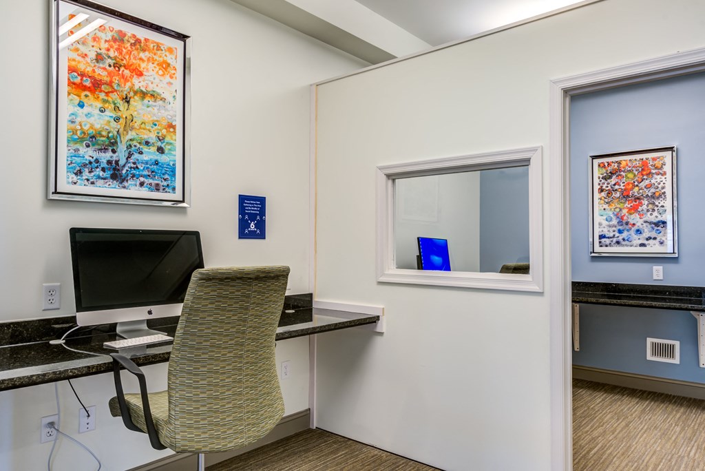 a room with a desk with a computer and a window