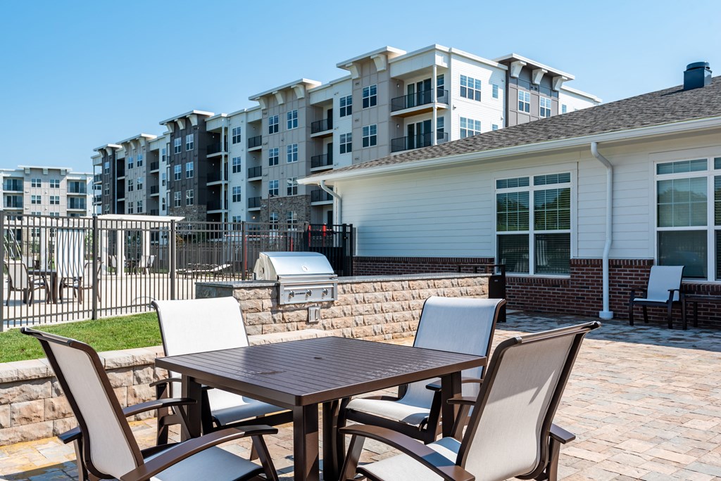 a patio with a table and chairs in front of an apartment building