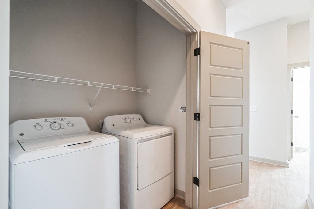 an empty laundry room with two washers and a dryer and a white door at Preston Ridge, Cary