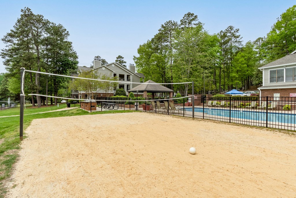 the volleyball court is in front of a pool and a fence