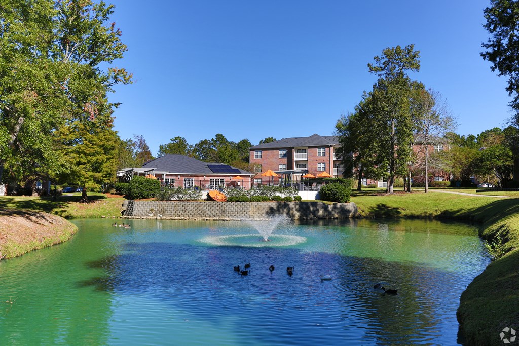 a fountain in the middle of a pond with a building in the background at Jamison Park, North Charleston, SC, 29406