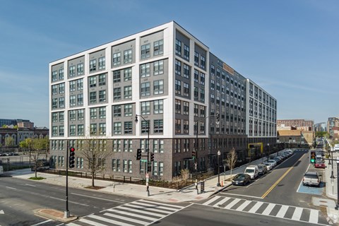 A street view of a modern building with a traffic light showing red.