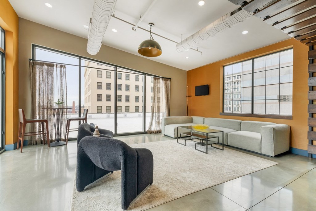 a living room with a couch and a chair in front of a window at The Harriet Apartments, Maryland, 21202