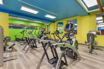 a gym with cardio equipment and weights in a building with yellow and green walls at The Harriet Apartments, Maryland, 21202