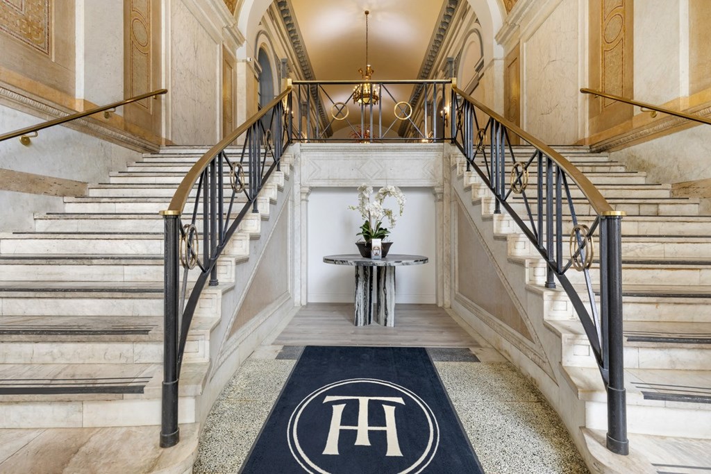 the lobby of a building with stairs and a rug with the h logo on it at The Harriet Apartments, Maryland