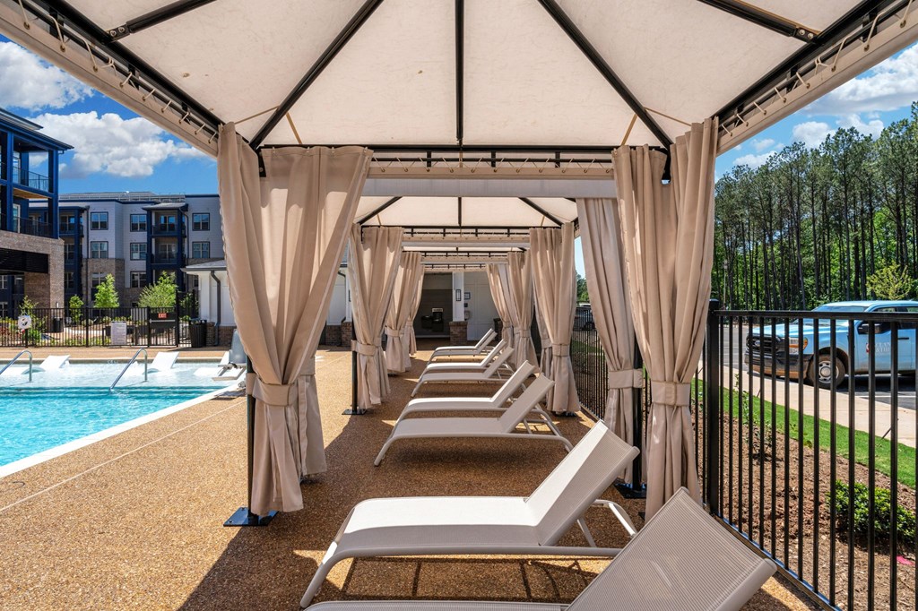 a row of lounge chairs under a canopy next to a swimming pool at Preston Ridge, Cary, 27513