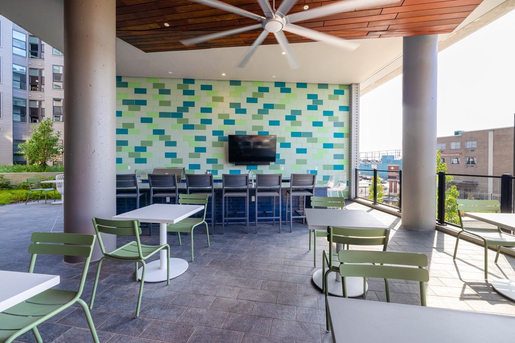 a patio with tables and chairs and a wall with a television at The Chase at Bryant Street, Washington District of Columbia