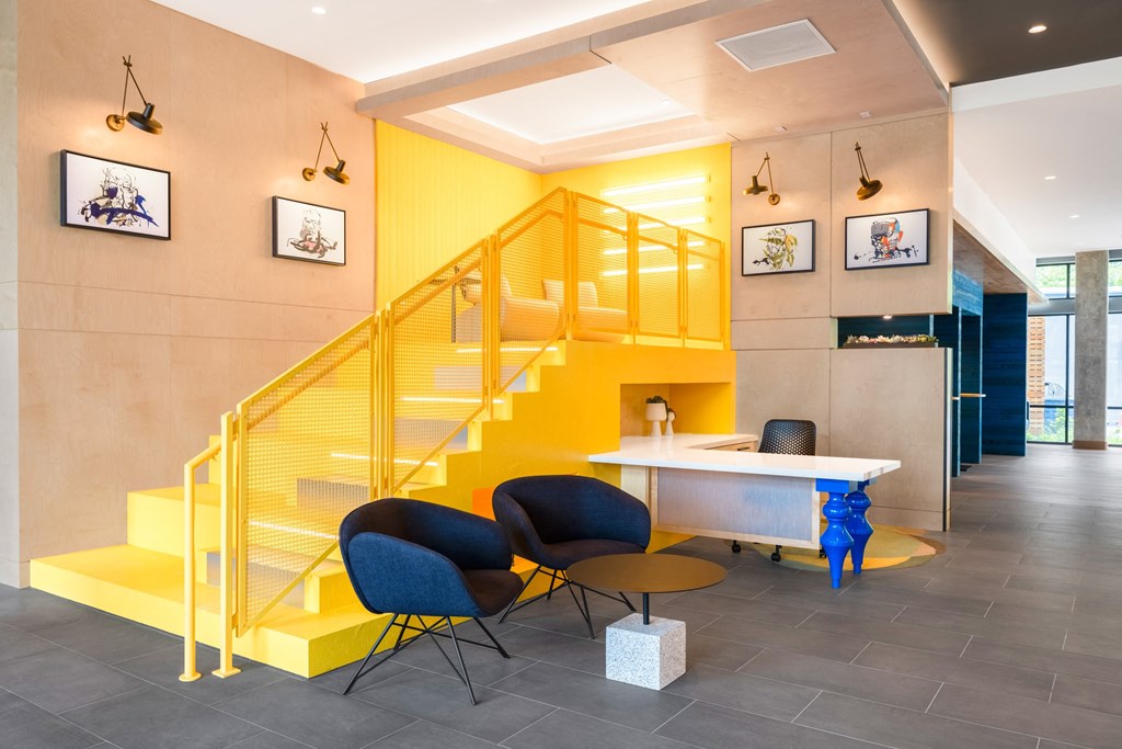 a yellow staircase in a lobby with chairs and a table at The Chase at Bryant Street, District of Columbia