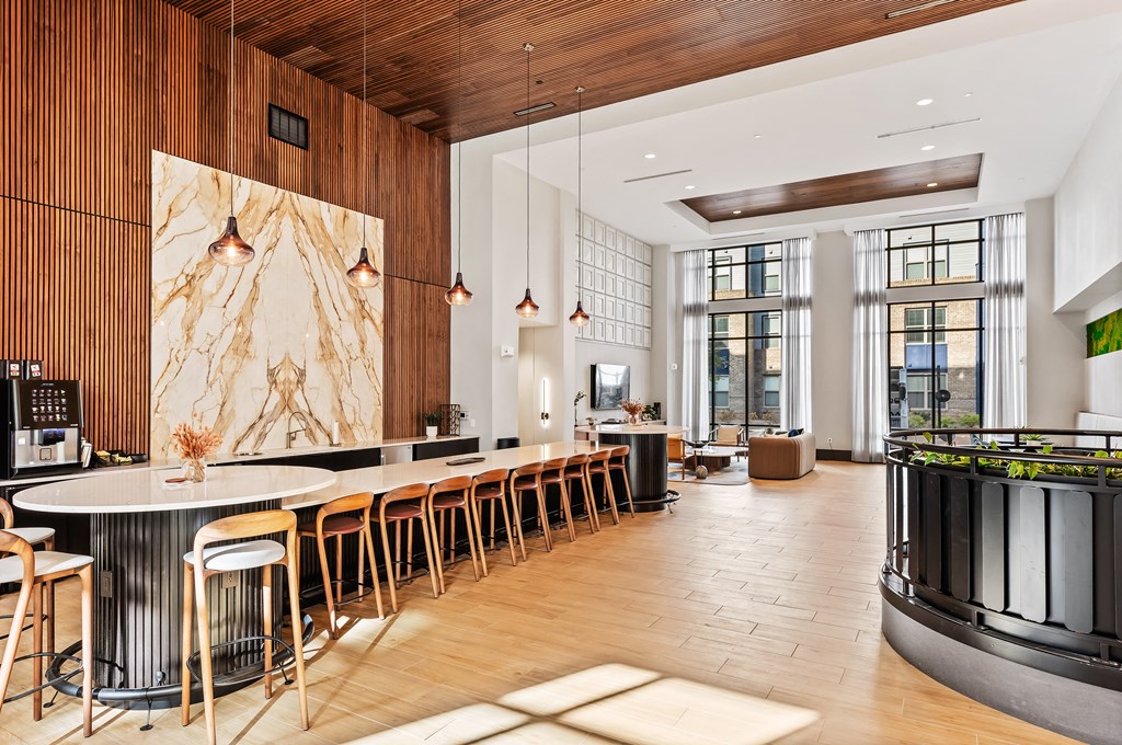 A modern kitchen with a long bar and wooden floors at the Preston Ridge Clubhouse in Cary, NC.
