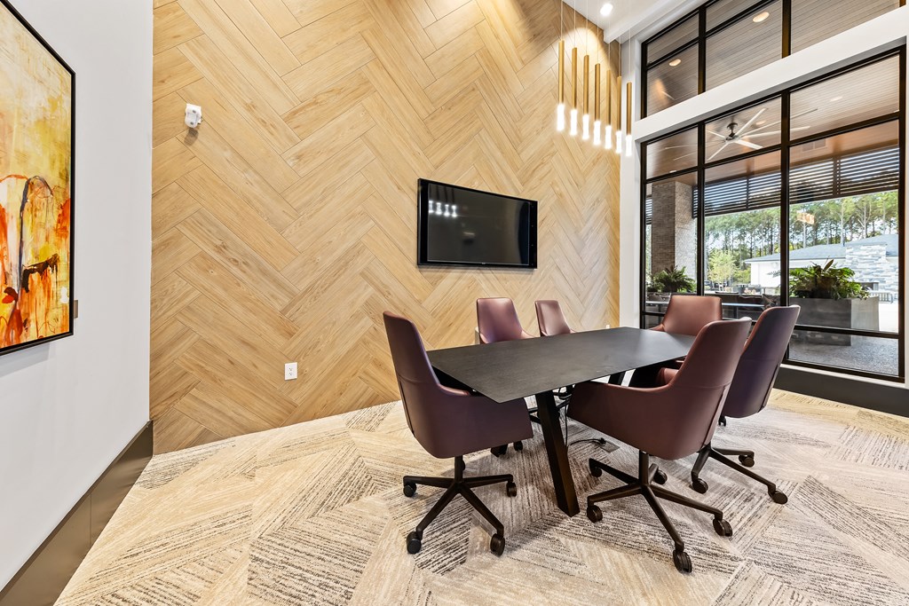 A conference room with a table and chairs and a TV on the wall at Preston Ridge Apartments.
