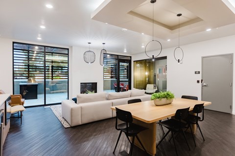 A modern dining room with a wooden table and black chairs.