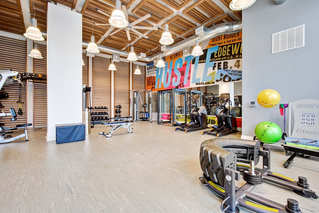 a gym with weights and cardio machines and a large wall with a sign on it at Coda at Bryant Street, Washington 