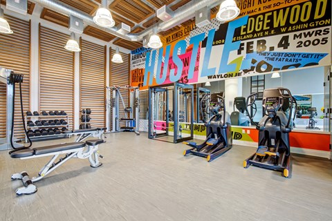 a gym with cardio machines and weights on the floor and a wall with a mural at Coda at Bryant Street, Washington, 20002