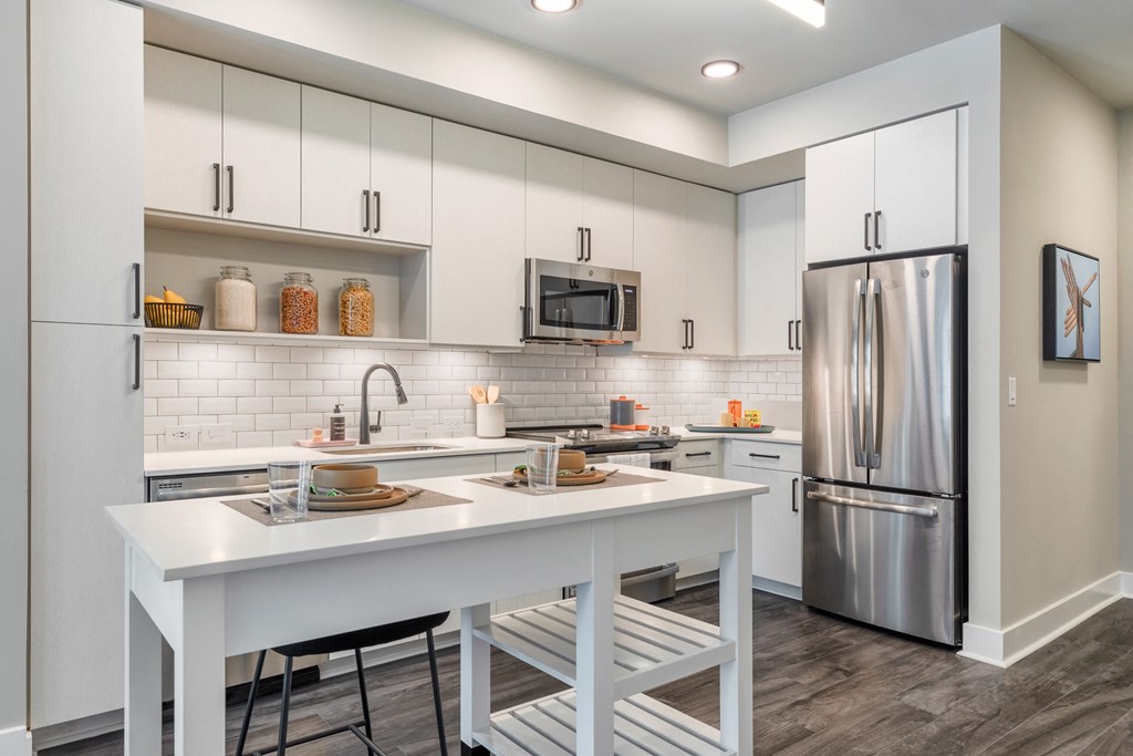 a kitchen with white cabinets and a white island and a refrigerator at Coda at Bryant Street, Washington