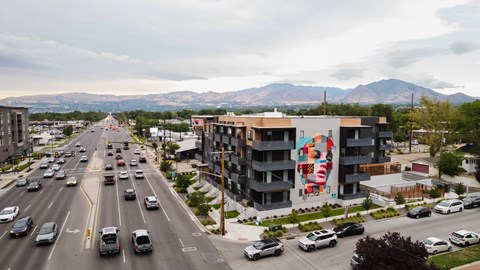 A busy street with cars and a large building with a mural on the side.
