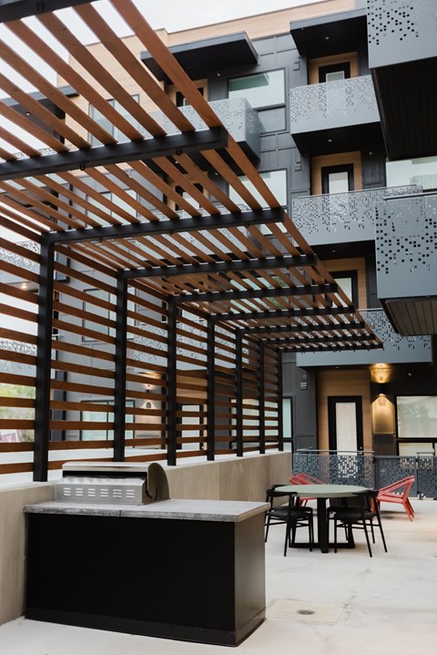 A modern outdoor kitchen area with a bar and chairs.