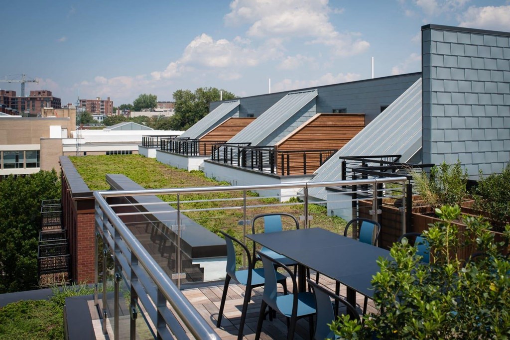 a rooftop terrace with tables and chairs and a green roof