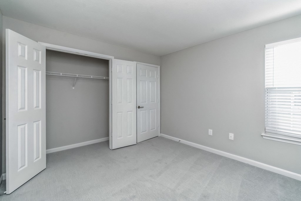 an empty bedroom with white doors and a closet at The Fields at Lorton Station, Virginia
