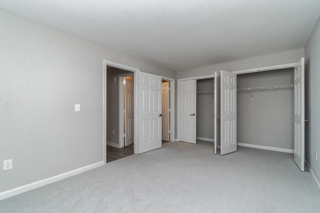 an empty bedroom with three closets and three doors