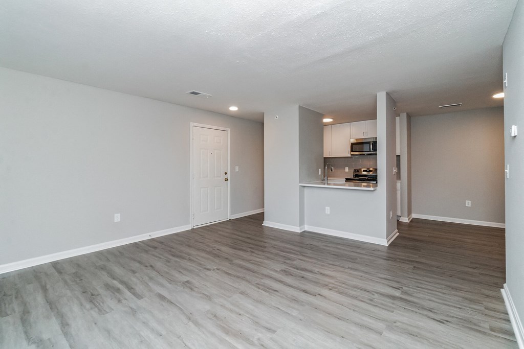 the living room and kitchen of an apartment with wood flooring at The Fields at Lorton Station, Virginia