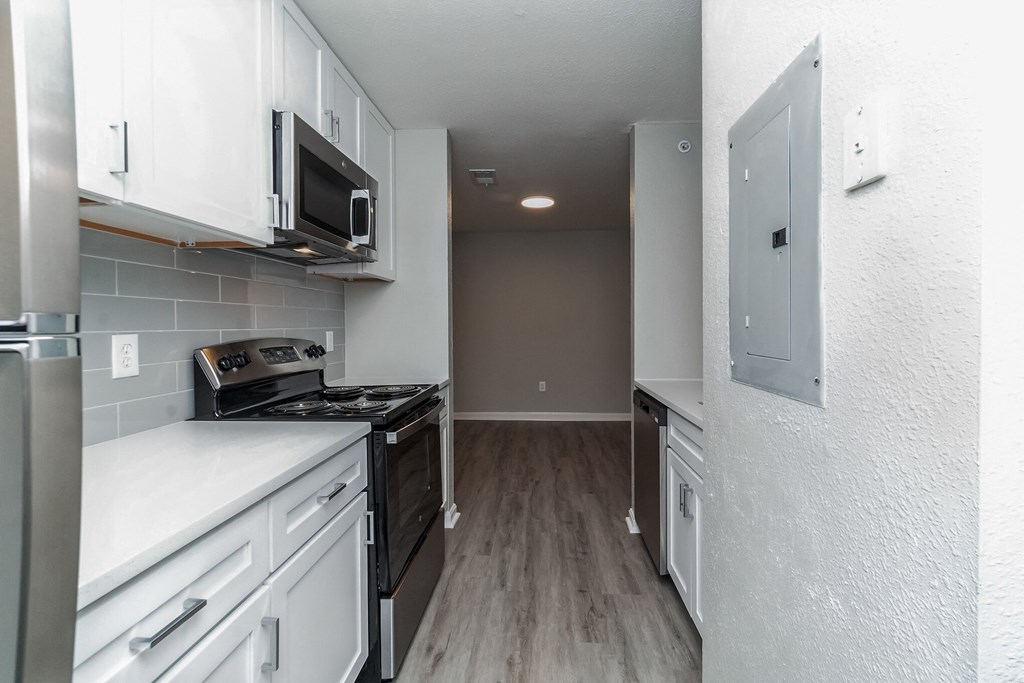 an empty kitchen with white cabinets and a black stove at The Fields at Lorton Station, Lorton, Virginia