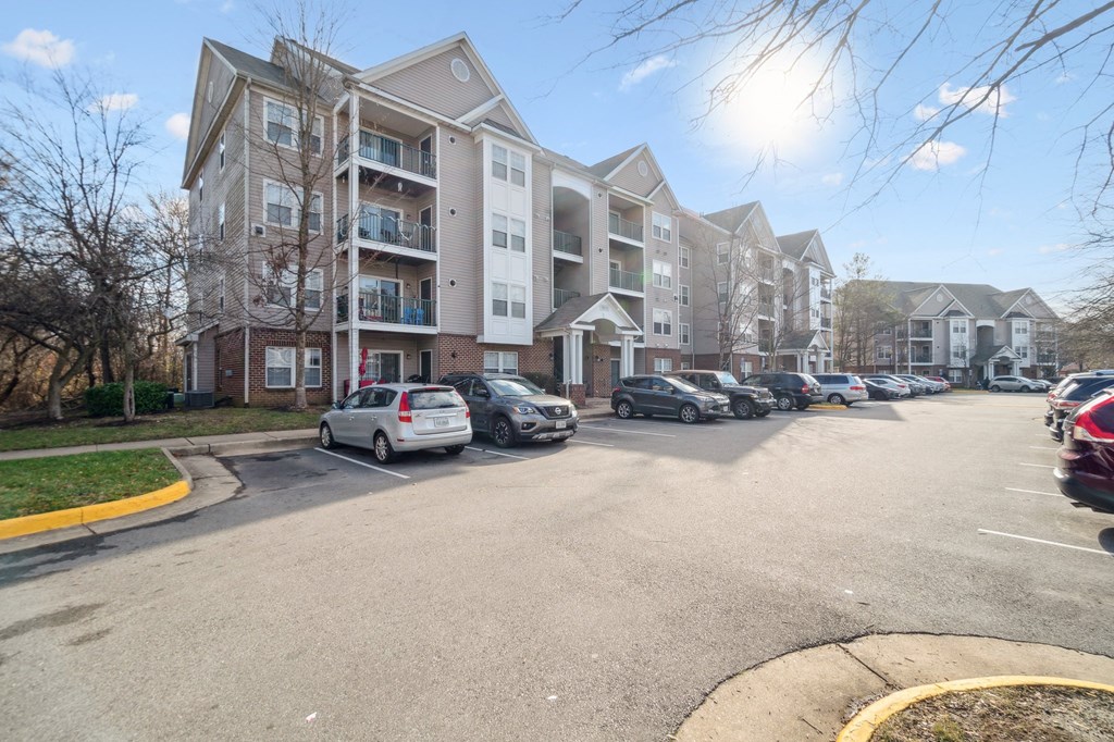 a large apartment building with cars parked in front of it at The Fields at Lorton Station, Lorton, VA, 22079