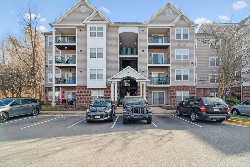 an apartment building with cars parked in front of it at The Fields at Lorton Station, Lorton, Virginia