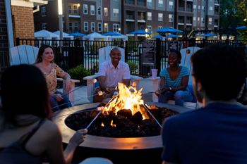 A Group of People are Sitting Around a Fire Pit on a Patio at The Aster Apartments, Cary, 27519