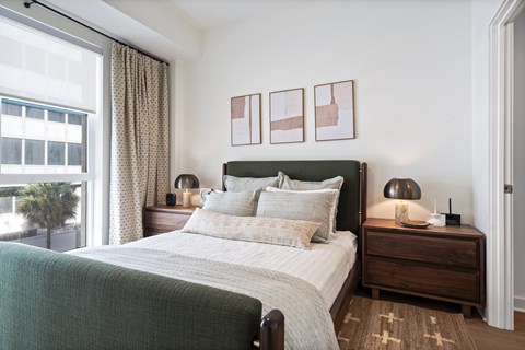 A bedroom with a large bed and a window overlooking a tree.