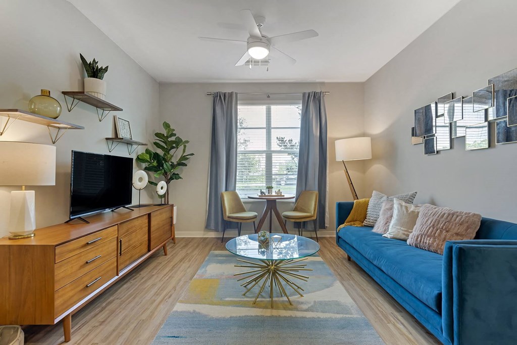 a living room with a blue couch and a coffee table in front of a window at Delamarre at Celebration, Celebration