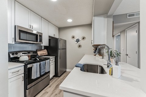 a white kitchen with stainless steel appliances and white counter tops