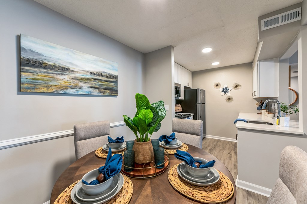 a dining area with a table and chairs and a kitchen in the background at Brampton Moors, Cary, NC