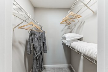 a walk in closet with a white bed and white pillows - Photo Gallery 20